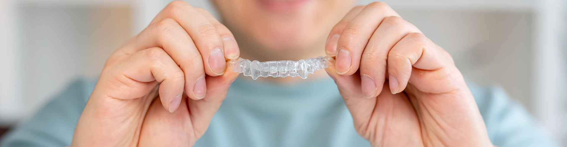 smiling man holding clear aligner.